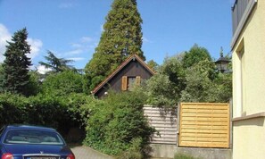 Ein Wohnhaus mit geneigtem Dach, einem Holzzaun und einem Auto auf der Auffahrt.
