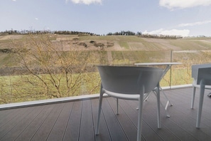 Ein Balkon mit Blick auf eine hügelige Landschaft, ein Tisch und zwei Stühle.
