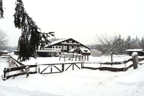 Ein schneebedecktes Gebäude mit einer Holzterrasse und einer Seilbahn.