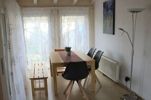 Un coin repas comprenant une table, des chaises, une petite plante et un radiateur.
