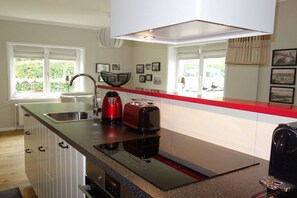 A modern kitchen with a built-in stove, a red toaster, and a kettle on the countertop. - Holiday apartment with 1 bedroom (Langballig)