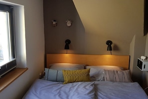 Ein Schlafzimmer mit einem hölzernen Kopfteil, einem Fenster und zwei Wandlampen.