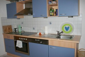 A kitchen with blue cabinets, a stainless steel sink, a dishwasher, and a coffee maker. - House "Bergwiese" Ingeborg Wetzel (Todtnau)