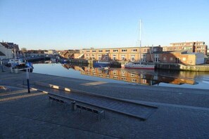 A waterfront marina with boats docked, a pedestrian walkway, and buildings in the background. - Holiday apartment in Wismar with Wi-Fi (Wismar)