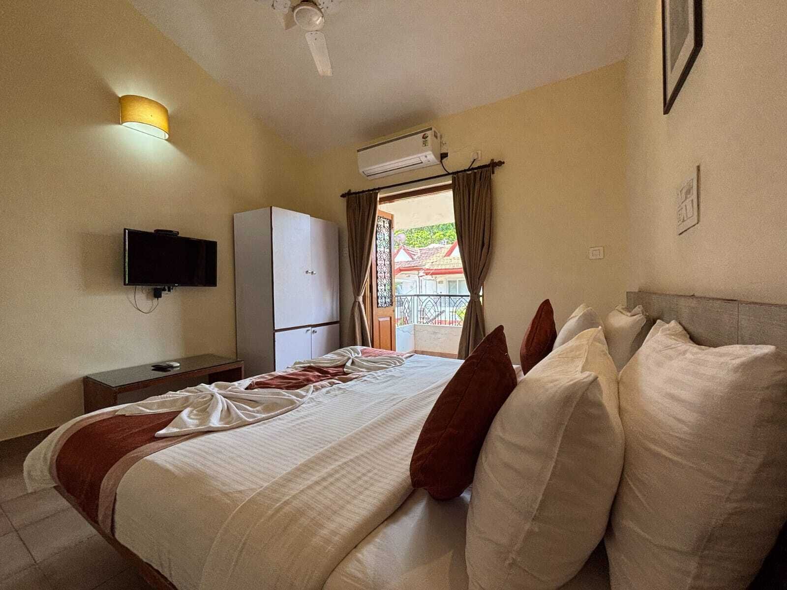 Een hotelkamer met een bed, een televisie, een kledingkast, een airconditioning en uitzicht op het omliggende landschap.
