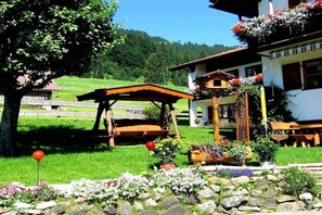 Ein traditionelles Chalet mit Holzterrasse, Steinmauern und Blumenkästen.