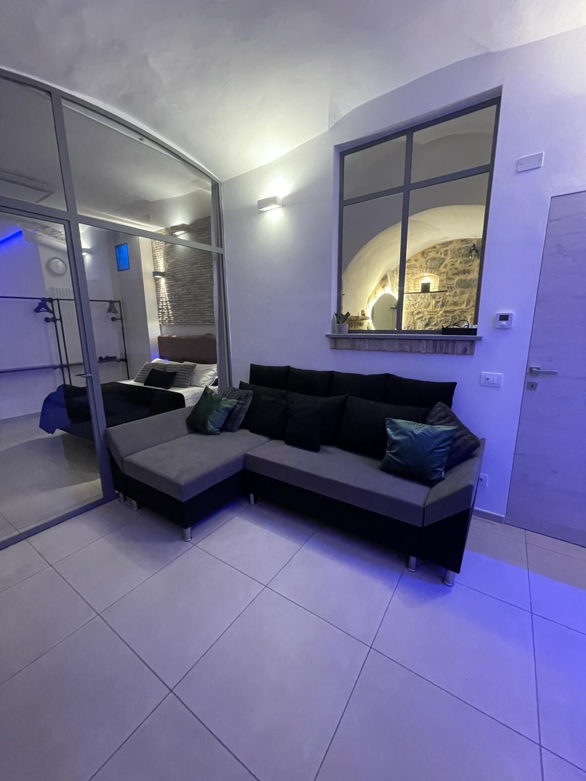 Un salon moderne avec un canapé d’angle, un grand miroir et un mur en pierre.