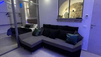 Un salon moderne avec un canapé d’angle, un grand miroir et un mur en pierre.