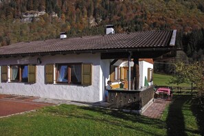 Ein weißes Gebäude mit einem Ziegeldach, einem Balkon und einem roten Backsteinweg, der zum Eingang führt.