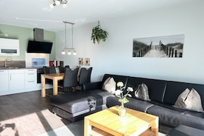 Ein modernes Wohnzimmer mit Sofa, Couchtisch und Essbereich.