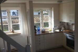 Une cuisine avec des meubles blancs, un évier et une cuisinière.