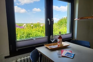Ein Zimmer mit einem großen Fenster, einem Tisch mit Tablett, einer Flasche und einem Glas.