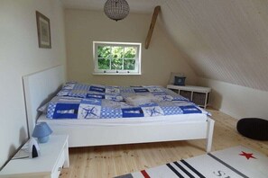 A bedroom with a bed, a window, a nightstand, a lamp, and a star-patterned rug. - Holiday apartment with 2 bedrooms (Hasselberg)