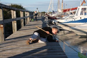 A wooden pier with boats docked, a person lying on the pier, and a child walking in the background. - Holiday apartment with 2 bedrooms (Hasselberg)