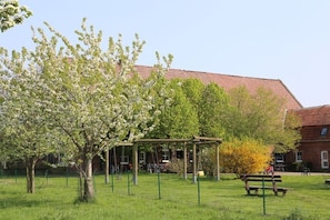 Ein Park mit Schaukeln, einem Picknicktisch und einem Gebäude mit rotem Dach im Hintergrund.