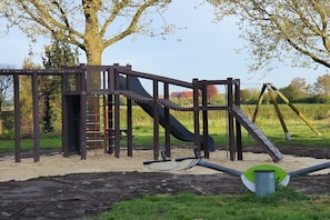 Ein Spielplatz mit Rutsche, Klettergerüst und Schaukeln.