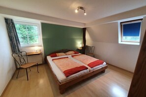 Ein Schlafzimmer mit einem hölzernen Bett, einem Schreibtisch, einem Stuhl und einem Fenster.