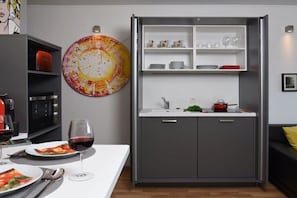 A compact kitchen with a built-in oven, a sink, and a countertop with a red pot. - ART OF LIFE the exclusive holiday apartment (Uppershausen)