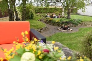 A garden patio with a fire pit, outdoor seating, and a stone pathway. - ART OF LIFE the exclusive holiday apartment (Uppershausen)