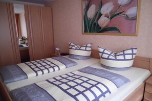 Ein Schlafzimmer mit einem Bett, Kissen, einem Nachttisch, einem Bild und einem Kleiderschrank.
