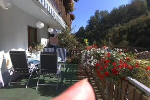 Eine Hotelterrasse mit Sitzgelegenheiten im Freien, einem Holzzaun und einem Blumenbeet.