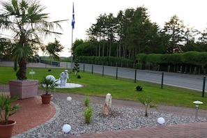 Ein angelegter Garten mit einer Palme, einer Statue und einer Fahnenmasten.