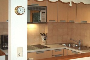 Eine Küche mit einer Mikrowelle, einem Spülbecken und einer Uhr an der Wand.