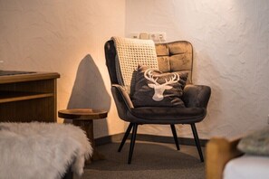 Ein gemütliches Zimmer mit einem Ledersessel, einem kleinen Holztischchen und einem flauschigen weißen Teppich.