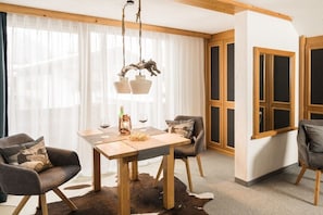 Ein Essbereich mit Holztisch, zwei Stühlen, einer Kronleuchter und einem Kuhfellteppich.