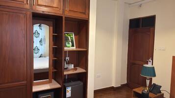 A hotel room with wooden cabinetry, a bed, a nightstand with a lamp, and a safe.