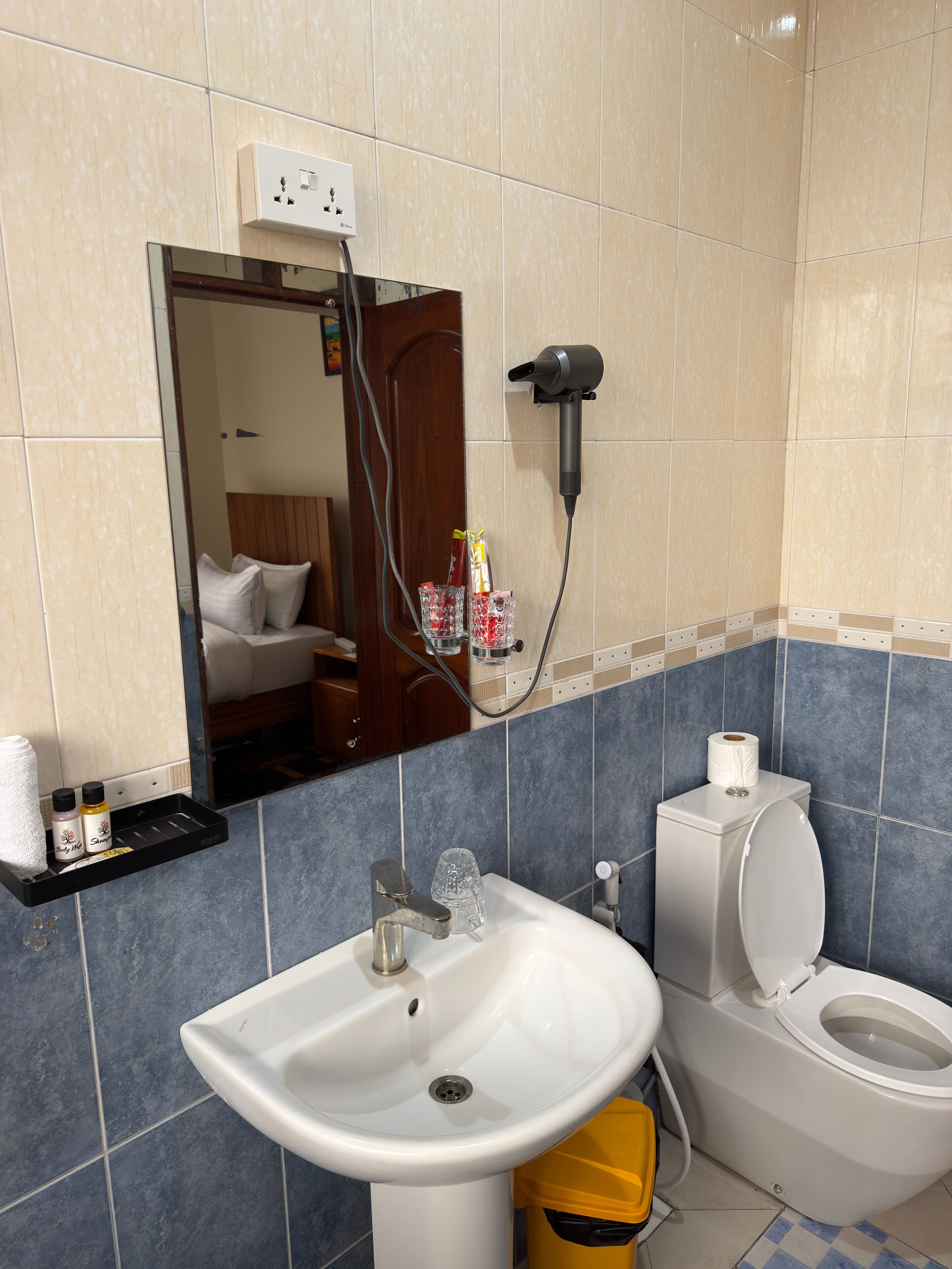 A bathroom with a sink, toilet, and a hairdryer mounted on the wall.