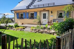 A building with a stone foundation, a blue door, and a number '1894' on the wall. - Holiday home Chalet Bianca (Bayern - Grafengehaig)