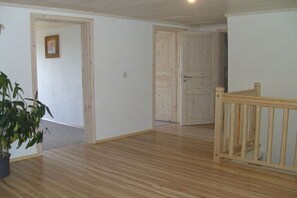 Ein Zimmer mit Holzboden, einer Holztreppe und einer Tür zu einem anderen Raum.