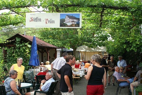 An outdoor seating area with tables and chairs, a signboard, and a building in the background. - at the Steffen-Prüm winery (Maring-Noviand)