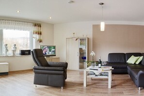 A modern living room with a sofa, armchair, coffee table, and a television. - at the Steffen-Prüm winery (Maring-Noviand)