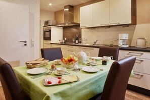 A dining area with a table set for four, a microwave, and a coffee maker in the background. - at the Steffen-Prüm winery (Maring-Noviand)