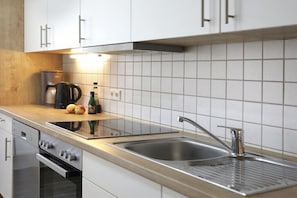 Eine moderne Küche mit weißen Schränken, einer Edelstahl-Spüle und einem eingebauten Backofen.