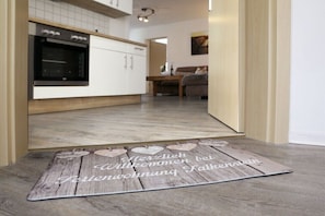 Eine moderne Küche mit weißen Schränken, einem schwarzen Backofen und einer Holzdusche mit Text.