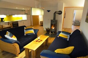 Ein Wohnzimmer mit zwei Sofas, einem Holztisch, einem Fernseher und einem Kamin.