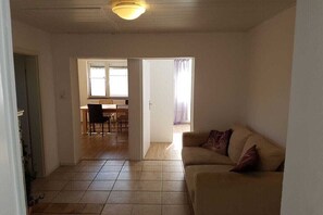 A living room with a sofa, a dining area with a table and chairs, and a kitchen in the background. - Holiday apartment in Werbach with barbecue (Werbach)