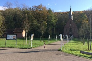 Eine Kirche mit einem hohen Kirchturm, ein kleines Gebäude zur Linke und ein Weg dorthin.