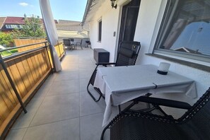 Ein Balkon mit Tisch und Stühlen, ein Fenster und Blick auf eine Wohngegend.
