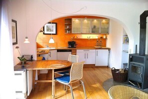 A compact kitchen with an archway, a dining table with chairs, a stove, and a small dining area. - Apartment in Obervolkach with swimming pool (Obervolkach)