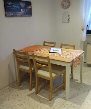 Uma área de refeições com uma mesa, cadeiras e um relógio na parede.