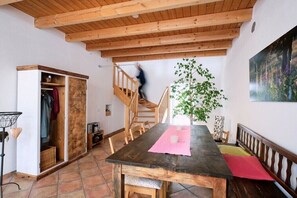 Ein Essbereich mit Holztisch, Stühlen, einer Treppe und einer Pflanze.
