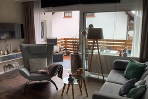 A modern living room with a sofa, armchair, and floor lamp. - A short break at Schöneck (Fischbach)