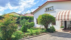 A white building with a red roof, a garden with various plants and flowers, and a covered outdoor seating area. - Casa degli Orti in Venice (Dolo)