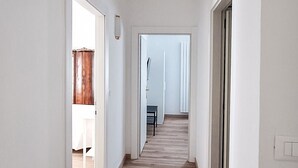 A hallway with wooden flooring, white walls, and doors leading to other rooms. - Casa degli Orti in Venice (Dolo)