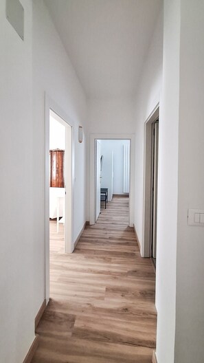 Ein Korridor mit Holzdielen, weißen Wänden und Türen zu weiteren Räumen.