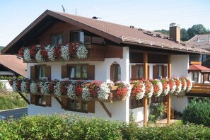 A two-story building with a balcony adorned with flower baskets. - Holiday apartment with 2 bedrooms (Fischen)